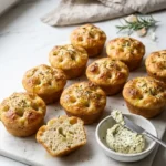 Rosmarin-Knoblauch-Focaccia-Muffins serviert mit Kräuterbutter — Aufgeschnittener Muffin zeigt die weiche Krume.