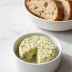 Schnelle Kräuterbutter mit Knoblauch serviert mit frischem Sauerteigbaguette — perfekt für das nächste Grillfest.