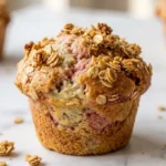 Bananen-Erdbeermuffins frisch gebacken — goldbraune Muffins mit sichtbaren Fruchtschichten und krossem Müsli-Topping.