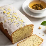 Zitronenkuchen mit Mohn serviert mit Earl Grey Tee — Ein aufgeschnittenes Kuchenquadrat zeigt die feine Mohn-Krume neben Tee.