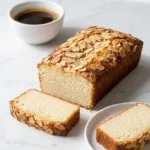 Buttermilchkuchen mit Mandeln serviert mit Filterkaffee — Ein saftiges Stück Blechkuchen liegt neben einer warmen Tasse Kaffee.