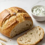 Brot aus der Heißluftfritteuse serviert mit frischer Kräuterquark — Eine abgeschnittene Brotscheibe liegt neben cremigem Quark.