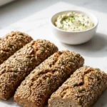 Körnerstangen mit Quark serviert mit Kräuterbutter — Aufgeschnittene Proteinstange zeigt das saftige Innere der Krume.