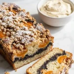 Mohn-Aprikosen-Schnitten serviert mit Vanillesahne — Ein aufgeschnittenes Kuchenquadrat offenbart die saftige Mohnfüllung neben Sahne.