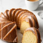 Zitronen-Joghurt-Kuchen serviert mit Filterkaffee — Eine abgeschnittene, flaumige Kuchenscheibe liegt appetitlich neben einer Tasse Kaffee.