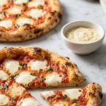 Sauerteigrest Pizza serviert mit Aioli — Ein abgeschnittenes Stück Pizza zeigt den dünnen, krossen Boden und luftigen Rand.