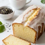 Zitronen-Joghurt-Kastenkuchen serviert mit Earl Grey Tee — Eine abgeschnittene Kuchenscheibe zeigt die saftige Krume.