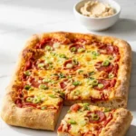 Zweierlei Blechpizza serviert mit Kräuterbutter — rechteckige, frisch geschnittene Pizzastücke angerichtet auf weißem Marmor.