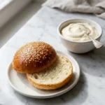 Burger-Buns serviert mit Vanille-Sahne — Ein aufgeschnittenes Brötchen präsentiert die luftige Krume.