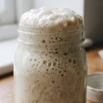 Erfolgreich umgezüchteter Sauerteig mit neuem Mehl, deutlich verdoppelt und bläschenreich.