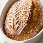 Saftiges Dinkel Joghurt Brot aus dem Topf frisch gebacken — knuspriges ovales Brot mit Blatt-Muster.