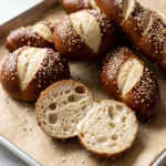 Dinkel-Laugenbrötchen und Laugenstangen frisch aus dem Ofen — glänzende kastanienbraune Kruste mit Brezelsalz