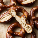 Echte deutsche Laugenbrezeln frisch gebacken auf dem Backblech — tiefbraune glänzende Kruste mit grobem Brezelsalz