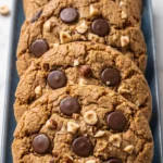 Haselnuss-Schoko-Cookies mit Sauerteig frisch gebacken — rissige Kekse gestapelt auf einer blauen Servierplatte auf Marmor