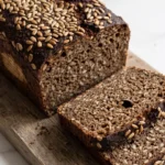 Kerniges Schwarzbrot mit Sauerteig frisch gebacken — saftiges Kastenbrot in Scheiben geschnitten mit Sonnenblumenkernen