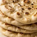 Luftig-weiches Naan-Brot frisch gebacken — gestapelte Pfannenfladen mit Knoblauchbutter.