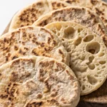 Goldbraune Pfannenbrote auf Holzbrett aus der Froschperspektive.