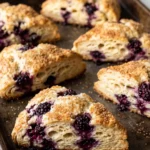 Saftige Sauerteig-Scones mit frischen Brombeeren und Knusperzucker auf dem Backblech.