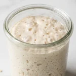 Sauerteig mit Apfelwasser frisch gebacken — aktiver, cremiger Weizensauerteig im Glas.
