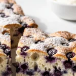 Schneller Heidelbeerkuchen vom Blech frisch gebacken — saftige Kuchenstücke mit Puderzucker