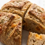 Schnelles Airfryer-Brot ohne Hefe frisch gebacken — runder Laib mit Cheddar, Rosmarin und Haferflocken-Kruste