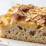 Apfelkuchen mit Sauerteig frisch gebacken — traditionelles Blechkuchenstück mit Mandelblättchen und Zimt