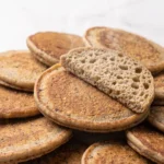 Roggen-Sauerteig-Pancakes frisch gebacken — dicke, weiche Frühstücks-Pancakes im Stapel auf weißem Marmor.