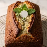 Zitronenkuchen mit Sauerteig frisch gebacken — kastenförmiger Kuchen mit tiefem Riss und Mohnpunkten auf weißem Marmor