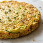 Zucchini-Pfannkuchen frisch gebacken — goldbraun ausgebackene Gemüsepfannkuchen garniert mit Thymian auf weißem Marmor.