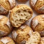 Brötchen über Nacht frisch gebacken — knusprige goldbraune Kruste mit rustikalem Kreuzschnitt auf Marmor.