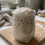 Perfekt gereifter, backbereiter Sauerteig mit vielen Blasen im Glas.
