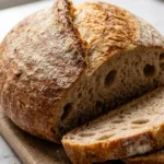 Frisch gebackenes Weizenbrot aus der Heißluftfritteuse, knusprig goldbraun auf einem Holzbrett angeschnitten.