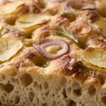 Herzhafte Sauerteig-Focaccia frisch gebacken mit knusprigen Kartoffelscheiben, roten Zwiebeln und Rosmarin.
