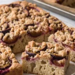 Klassischer Zwetschgenkuchen mit Knusper-Zimtstreuseln frisch vom Blech, in Stücke geschnitten.
