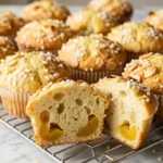 Saftige Mirabellen-Muffins mit Joghurt, Hagelzucker und knusprigen Mandelblättchen auf einem Kuchengitter.
