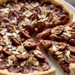 Zwetschgenkuchen mit Mürbteig fresh from the oven — golden plum tart with toasted almond slivers