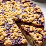 Einfacher Zwetschgenkuchen mit Streuseln aus der Springform, frisch gebacken mit zwei angeschnittenen Stücken.