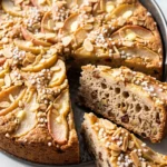 Apfel-Birnen-Kuchen aus Sauerteig frisch gebacken in der Form mit zwei angeschnittenen Stücken, belegt mit Mandelstiften und Hagelzucker.