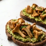 Deftiges Pfifferling-Brot: Getostetes Eiweißbrot mit Avocadocreme, Knoblauch-Pfifferlingen und Schnittlauch.