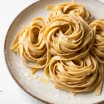 Frische selbstgemachte Dinkel-Tagliatelle aus Sauerteig, als Nester auf einem rustikalen Teller angerichtet.