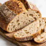 Saftiges Kartoffelbrot mit Sauerteig frisch aus dem Dutch Oven, knusprig aufgerissen und angeschnitten auf Holzbrett.