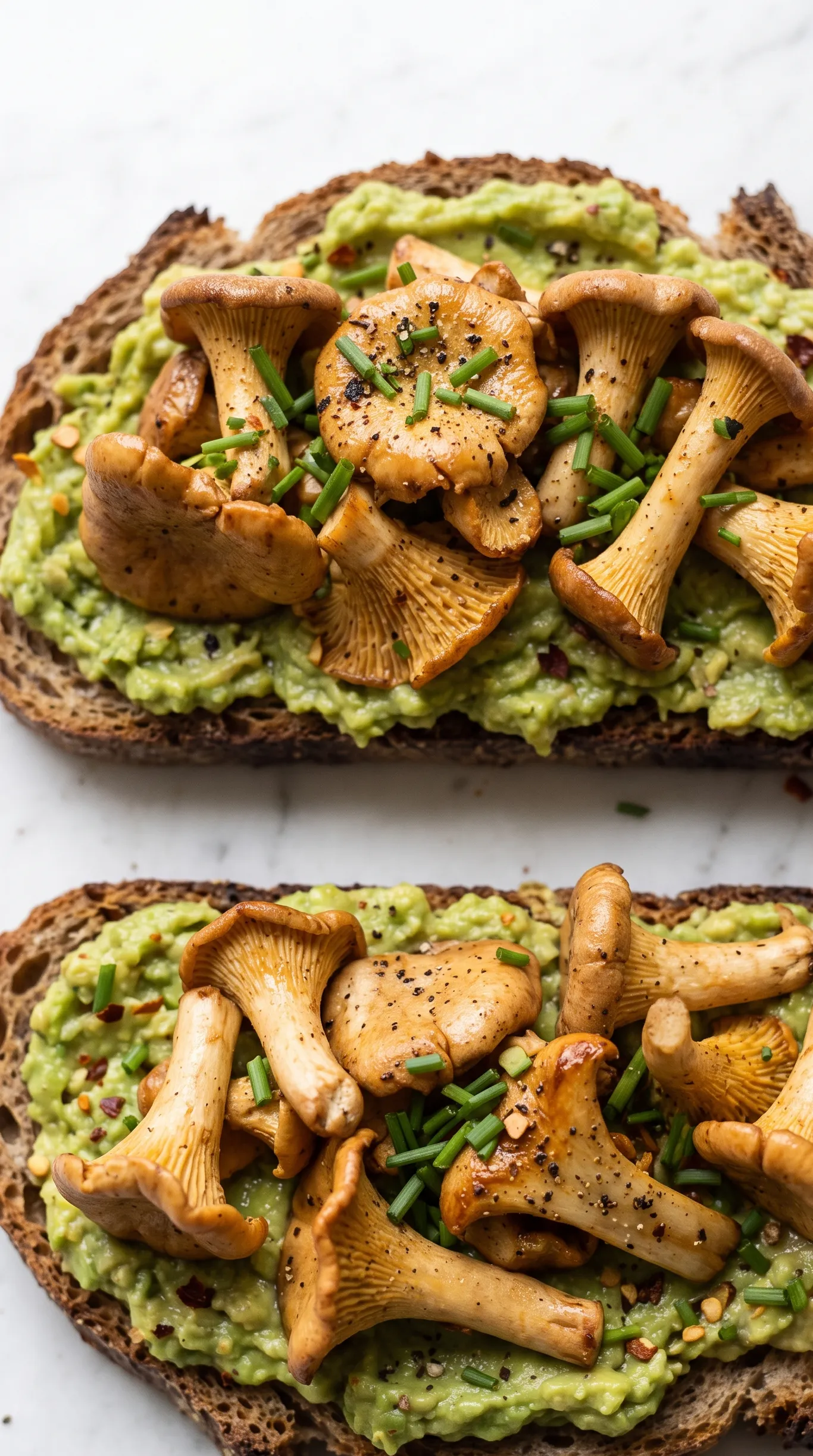 Nahaufnahme vom Pfifferling-Brot — goldbraun gebratene Knoblauch-Pilze, cremig grüne Avocado und Chiliflocken.
