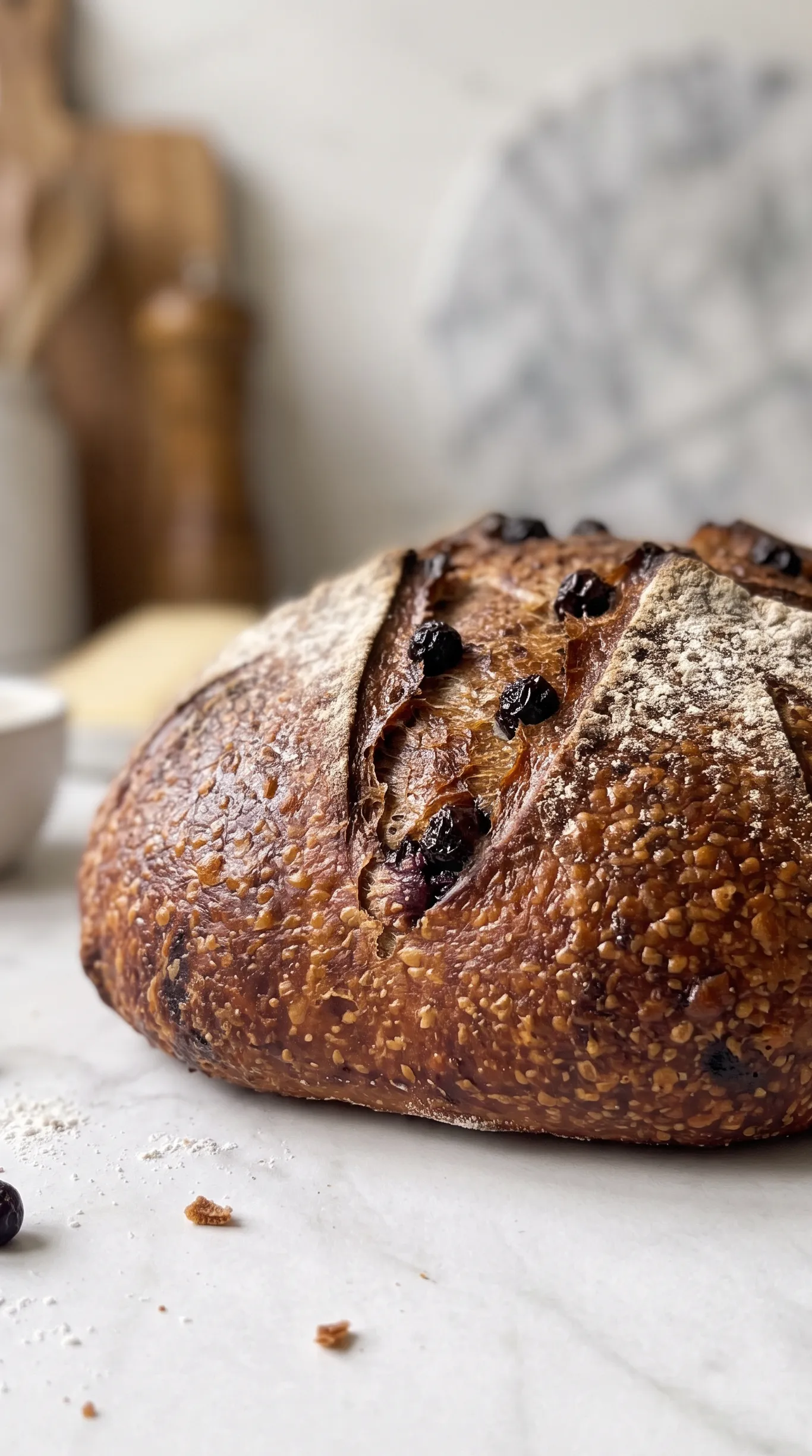 Aronia-Sauerteigbrot frisch gebacken — dunkle Kruste mit Einschneidung und Bemehlung